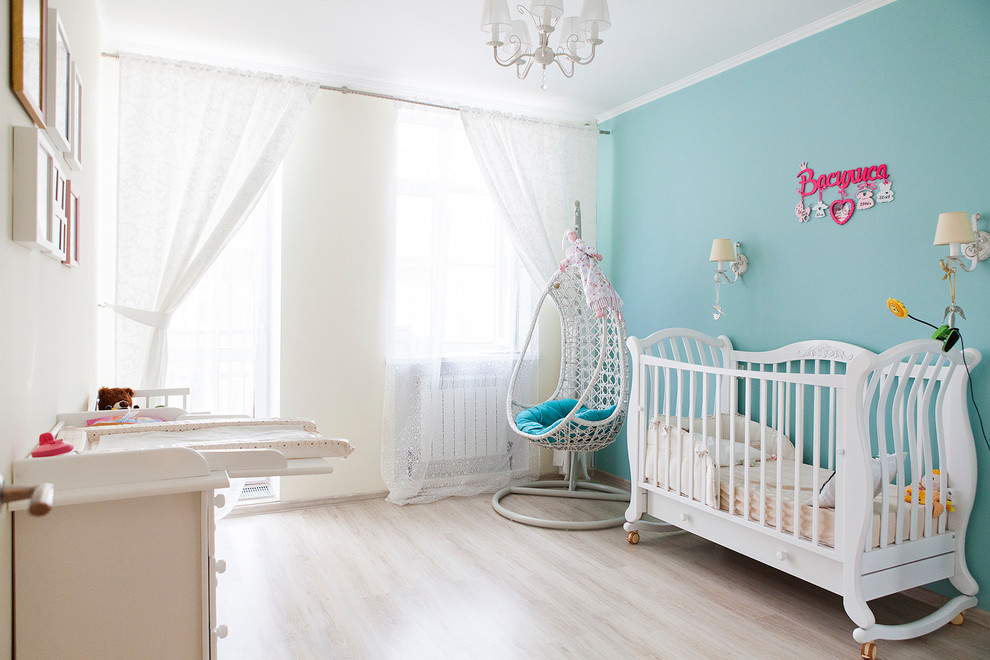 Imagen de habitación de bebé niña contemporánea con paredes azules, suelo de madera clara y suelo beige