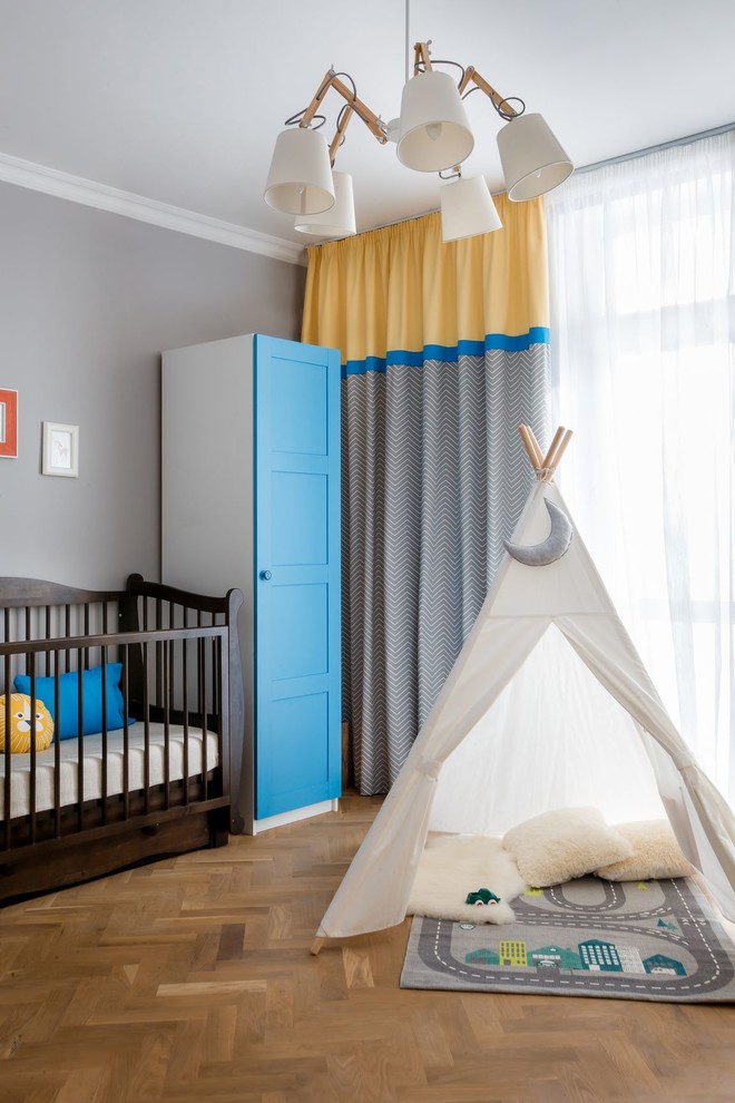 Mittelgroßes Modernes Babyzimmer mit grauer Wandfarbe, braunem Holzboden und braunem Boden in Sonstige