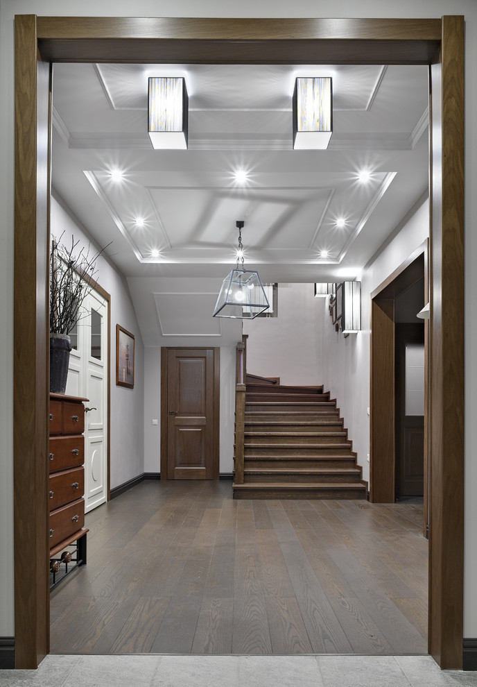 Стильный дизайн: коридор среднего размера в стиле неоклассика (современная классика) с белыми стенами, паркетным полом среднего тона и коричневым полом - последний тренд