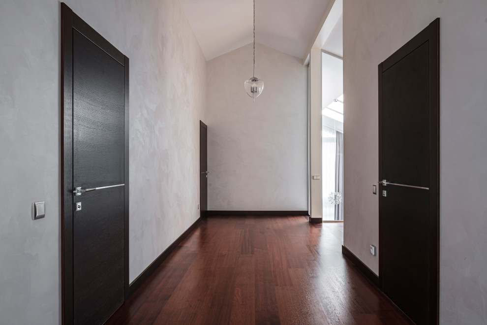 Réalisation d'un couloir design de taille moyenne avec un mur gris et un sol marron.