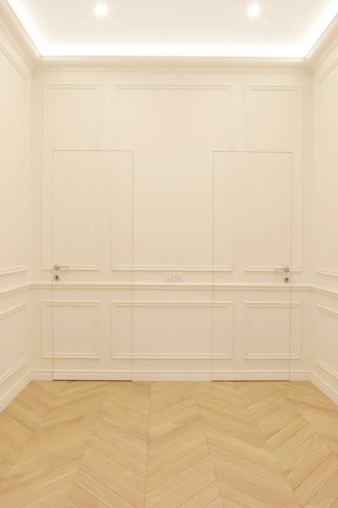 Aménagement d'un grand couloir classique avec un mur blanc, un sol en bois brun et un sol beige.