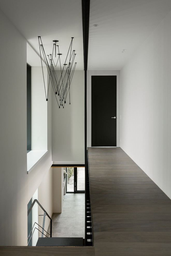 Idée de décoration pour un couloir design avec un mur blanc, parquet foncé et un sol marron.