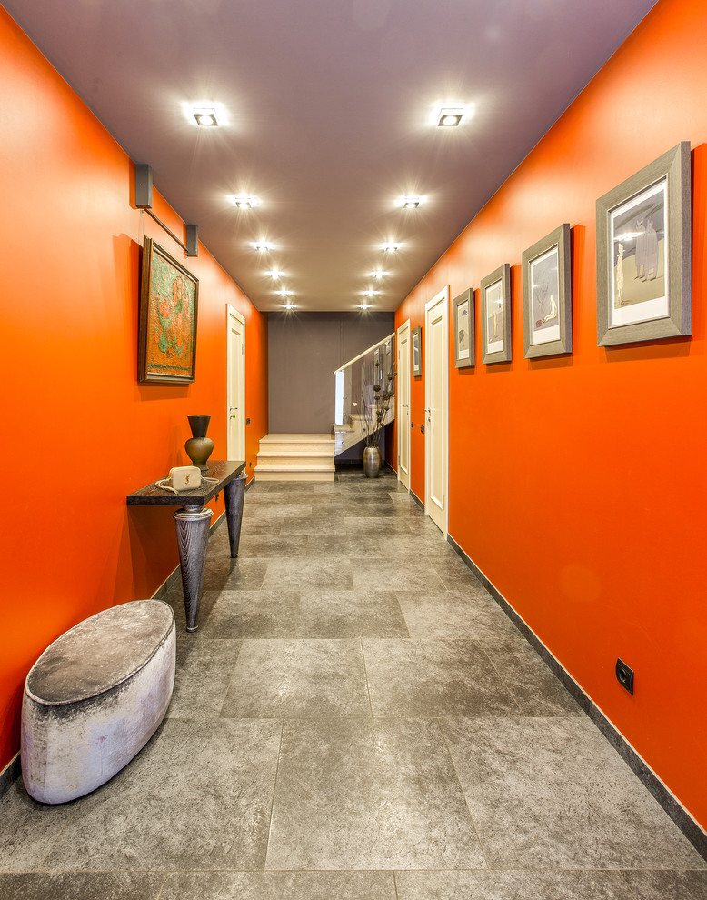 Стильный дизайн: большой коридор: освещение в стиле фьюжн с полом из керамогранита и оранжевыми стенами - последний тренд