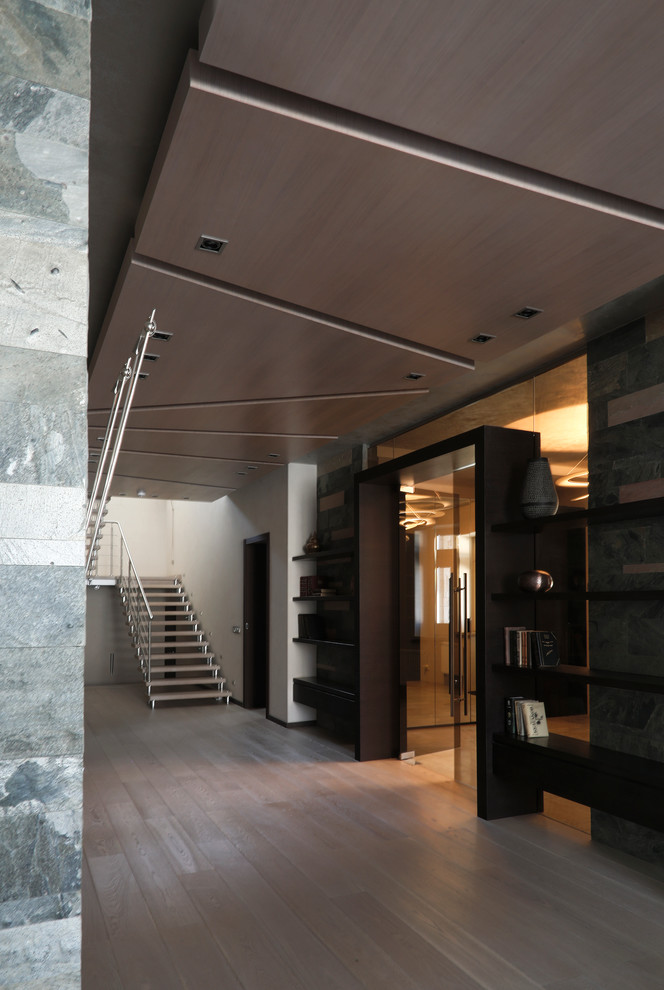 Imagen de recibidores y pasillos contemporáneos extra grandes con paredes grises y suelo de madera clara