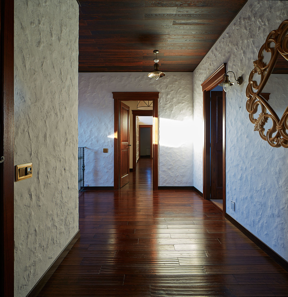 На фото: коридор в стиле кантри с белыми стенами, темным паркетным полом и коричневым полом с