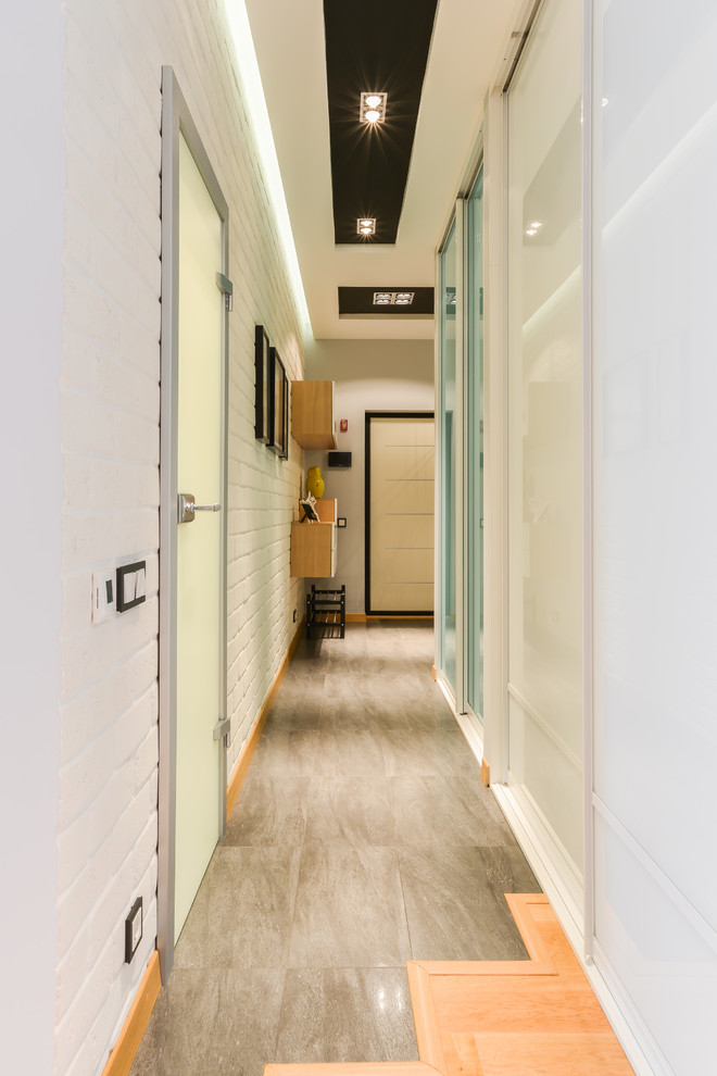 На фото: коридор среднего размера в современном стиле с белыми стенами и полом из керамогранита с
