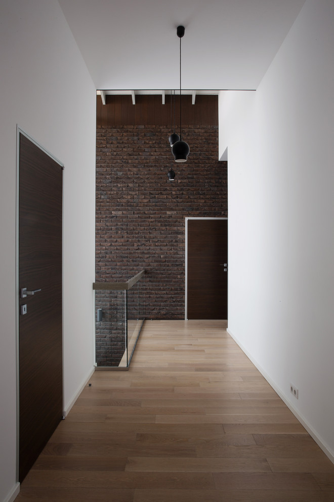 Modelo de recibidores y pasillos contemporáneos extra grandes con paredes blancas, suelo de madera clara y suelo marrón