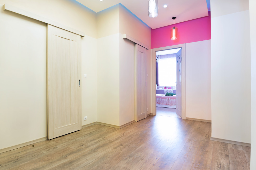 Idées déco pour un couloir contemporain de taille moyenne avec un mur multicolore, sol en stratifié et un sol marron.