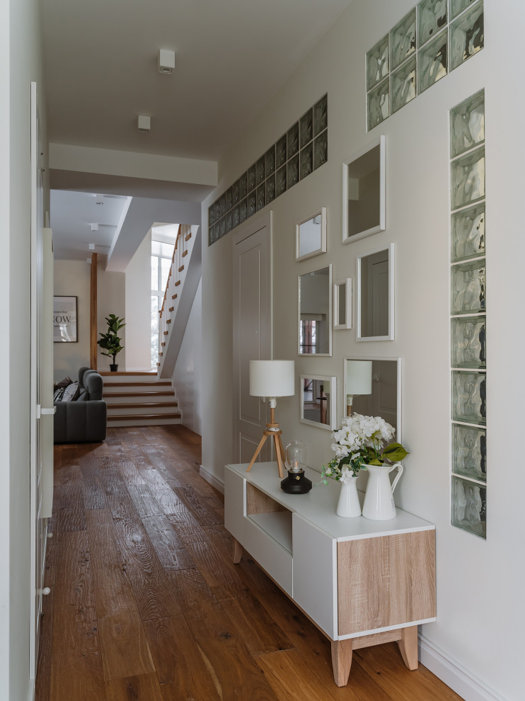 Example of a danish medium tone wood floor and brown floor hallway design in Moscow with white walls