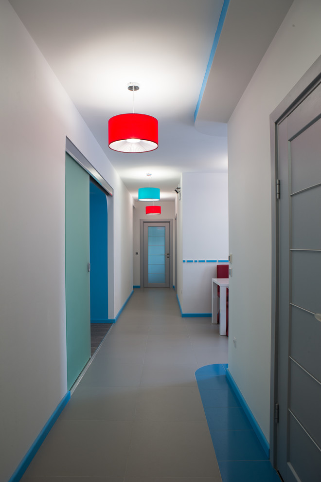 Cette image montre un couloir design de taille moyenne avec un mur blanc, un sol en carrelage de porcelaine et un sol gris.