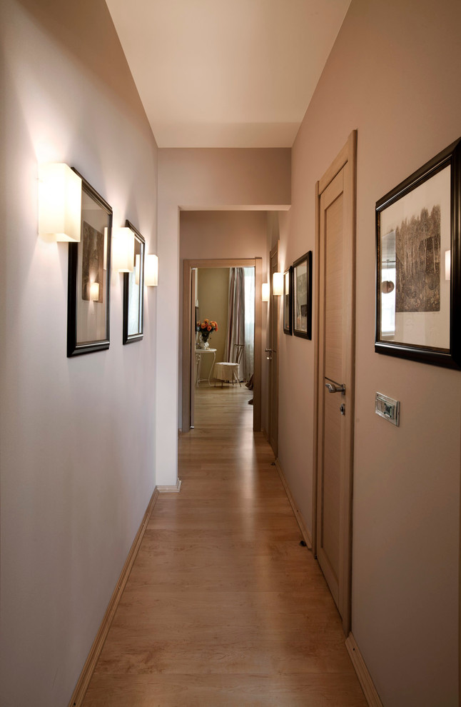 Ejemplo de recibidores y pasillos actuales de tamaño medio con paredes beige, suelo de madera clara y iluminación