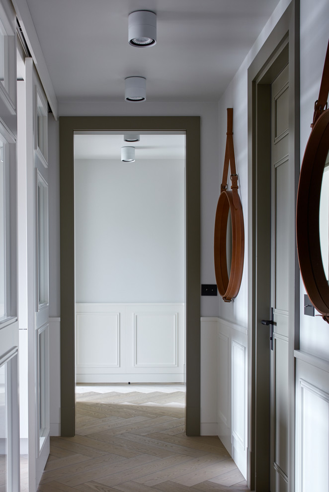 На фото: коридор: освещение в скандинавском стиле с белыми стенами и светлым паркетным полом