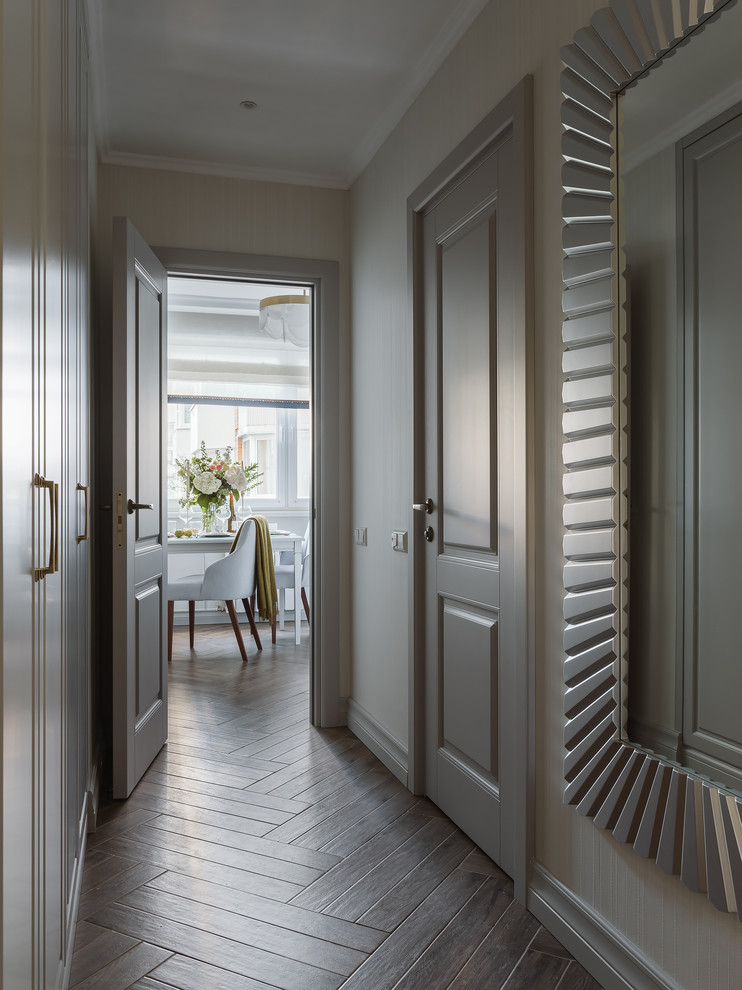 На фото: коридор среднего размера в стиле неоклассика (современная классика) с серыми стенами, полом из керамогранита и коричневым полом