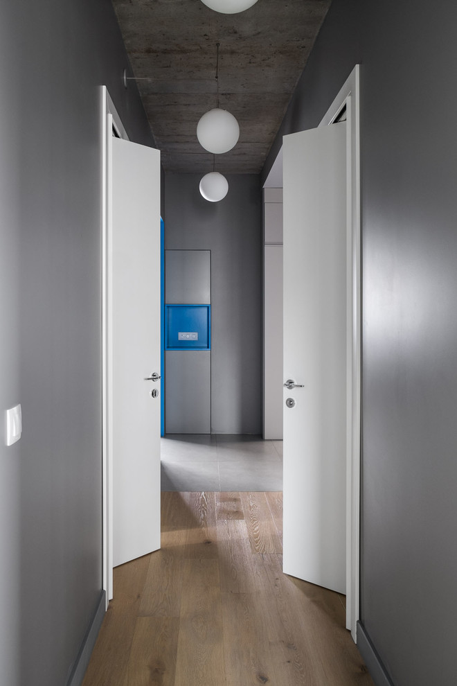 Идея дизайна: коридор в современном стиле с серыми стенами, паркетным полом среднего тона и коричневым полом