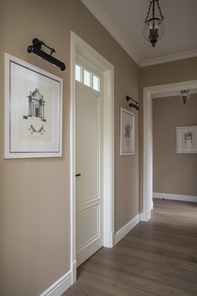 Cette photo montre un couloir chic avec un mur beige et un sol en bois brun.