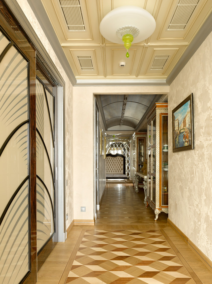 На фото: коридор в стиле неоклассика (современная классика) с бежевыми стенами, паркетным полом среднего тона и коричневым полом