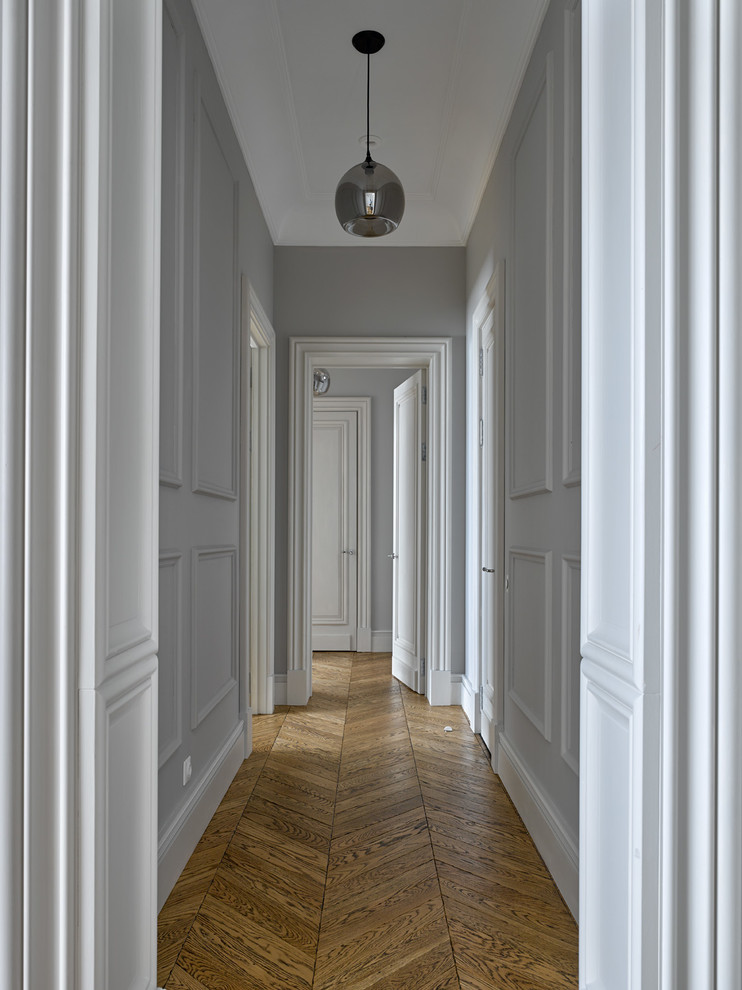 Diseño de recibidores y pasillos clásicos renovados con paredes grises, suelo de madera clara y suelo marrón