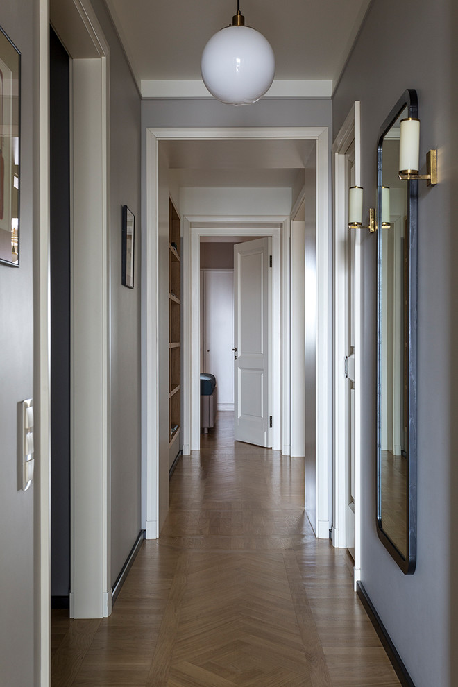 Idee per un ingresso o corridoio minimal di medie dimensioni con pareti grigie e pavimento in legno massello medio
