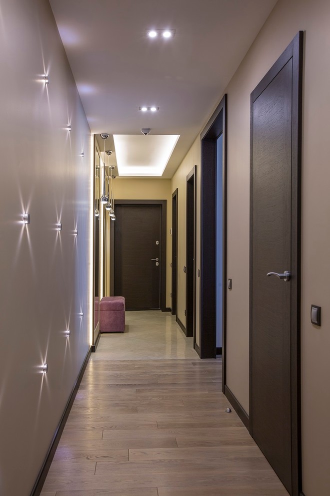 Inspiration pour un couloir design avec un mur beige et parquet clair.