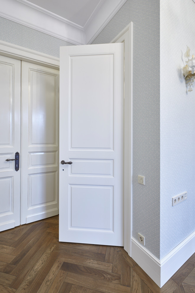 Стильный дизайн: большой, узкий коридор в классическом стиле с серыми стенами, паркетным полом среднего тона и коричневым полом - последний тренд