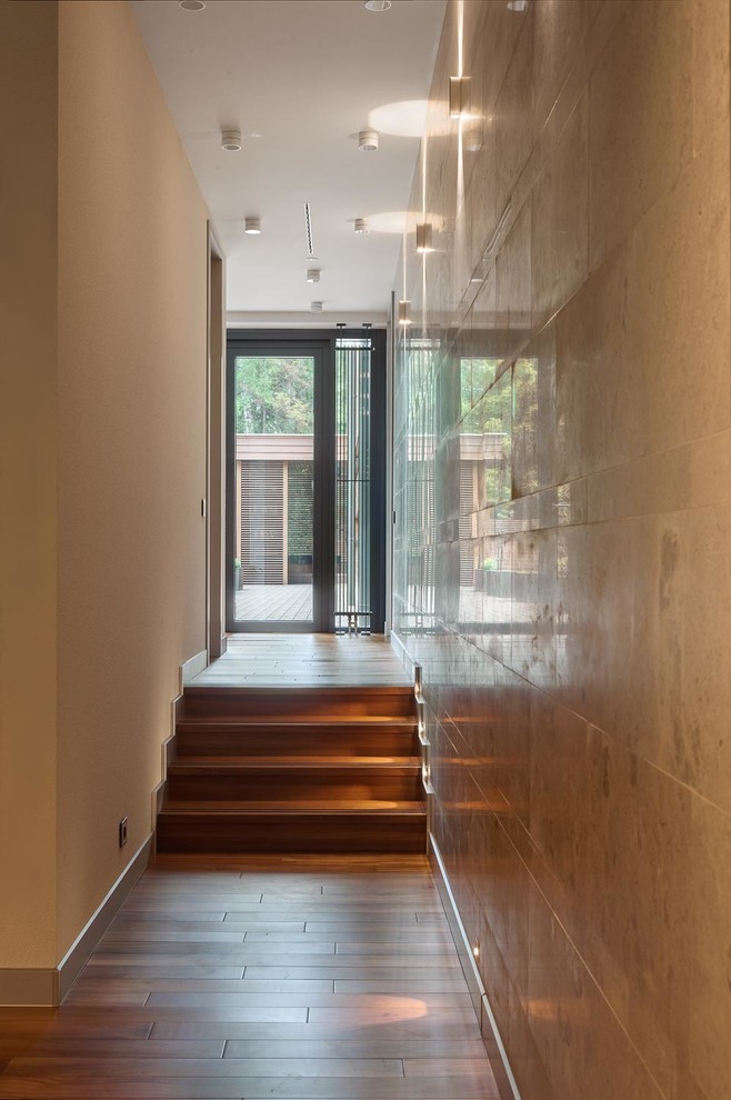 На фото: большой коридор в современном стиле с бежевыми стенами, паркетным полом среднего тона и коричневым полом