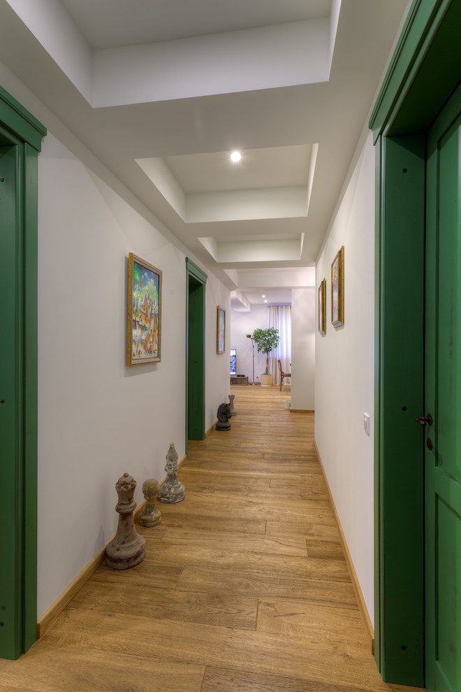 Immagine di un ingresso o corridoio design di medie dimensioni con pareti bianche e pavimento in legno massello medio