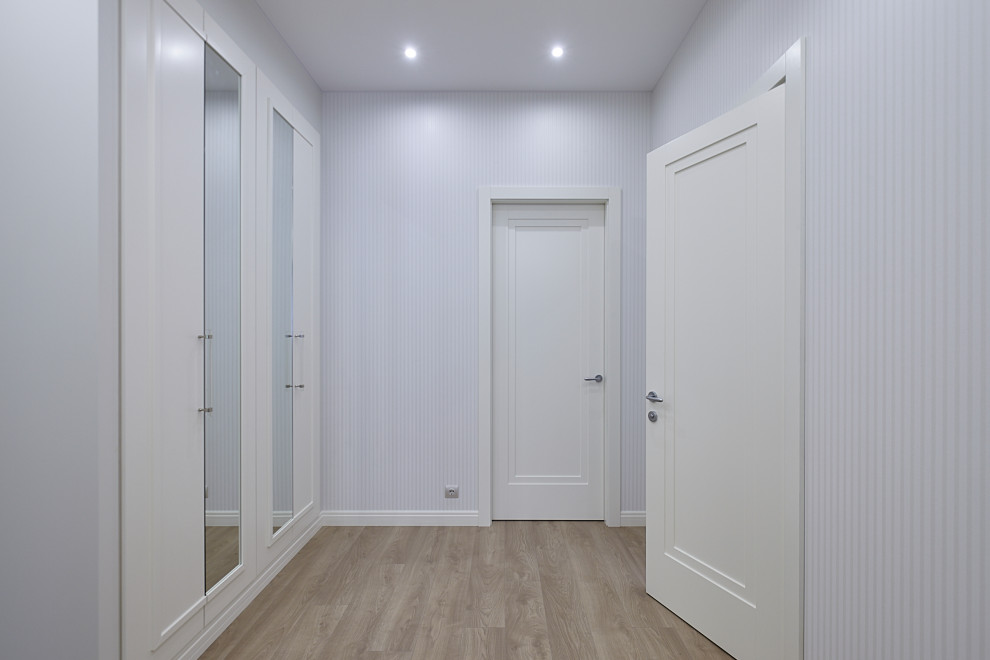 На фото: коридор среднего размера в стиле неоклассика (современная классика) с белыми стенами, полом из ламината и бежевым полом