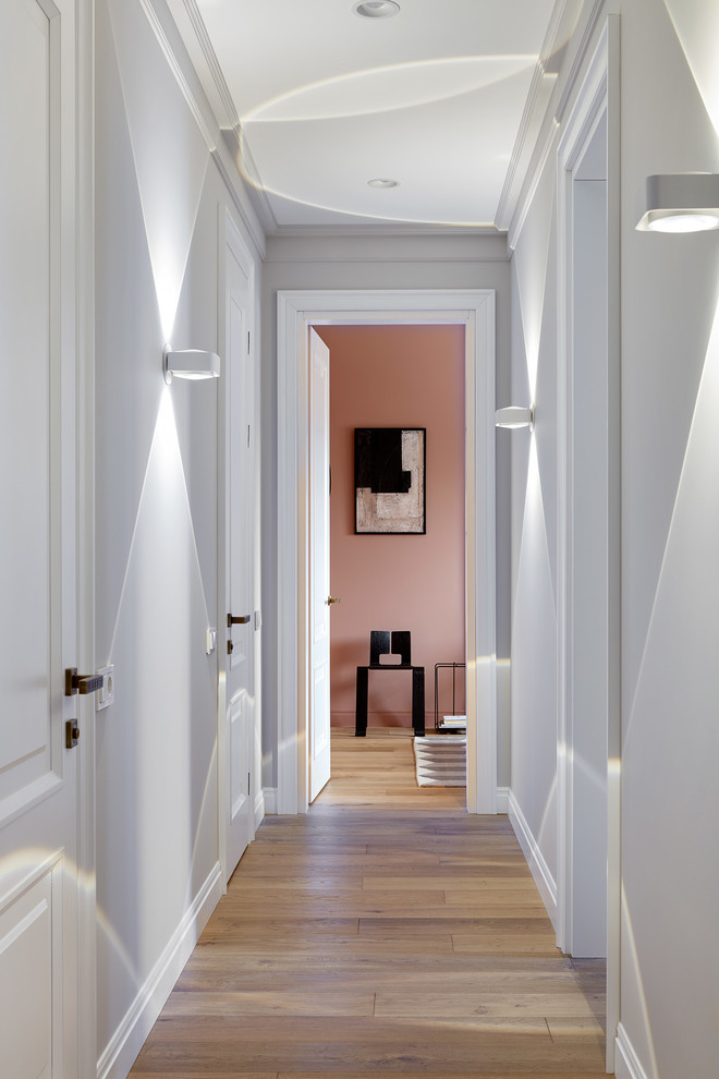Свежая идея для дизайна: коридор: освещение в стиле неоклассика (современная классика) с паркетным полом среднего тона, коричневым полом и розовыми стенами - отличное фото интерьера