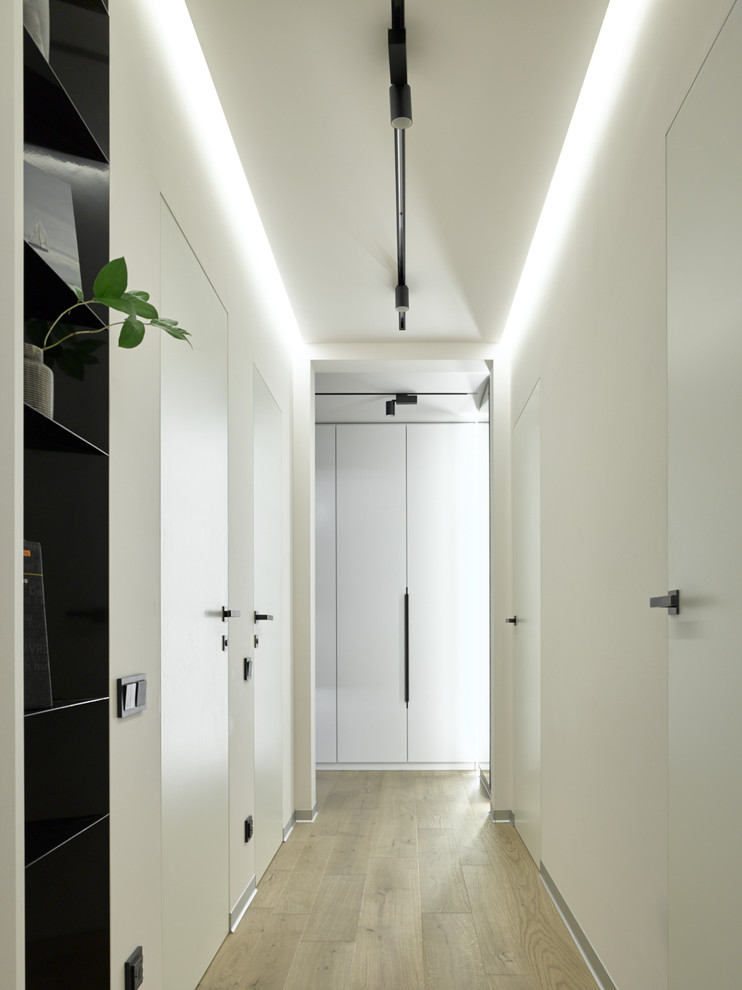 Cette image montre un couloir design avec parquet clair, un sol beige et un mur blanc.