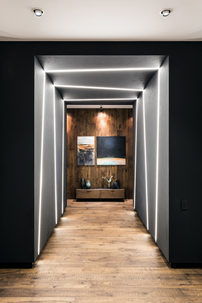 На фото: коридор среднего размера: освещение в современном стиле с черными стенами, паркетным полом среднего тона и коричневым полом с
