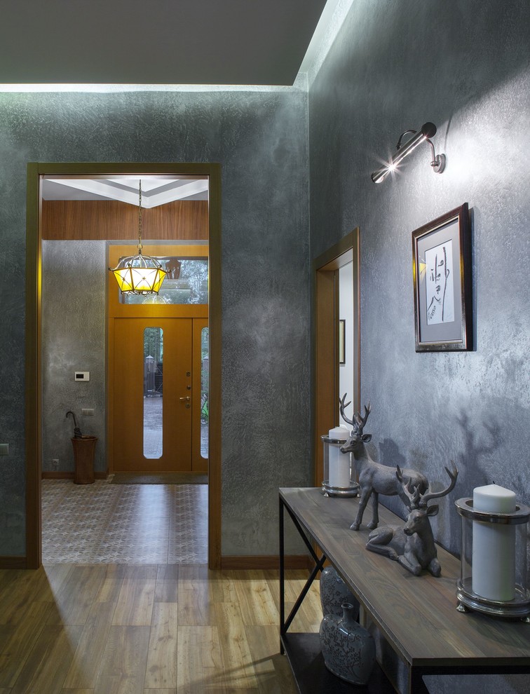 Cette photo montre un couloir tendance avec un mur gris, un sol en carrelage de porcelaine et un sol marron.