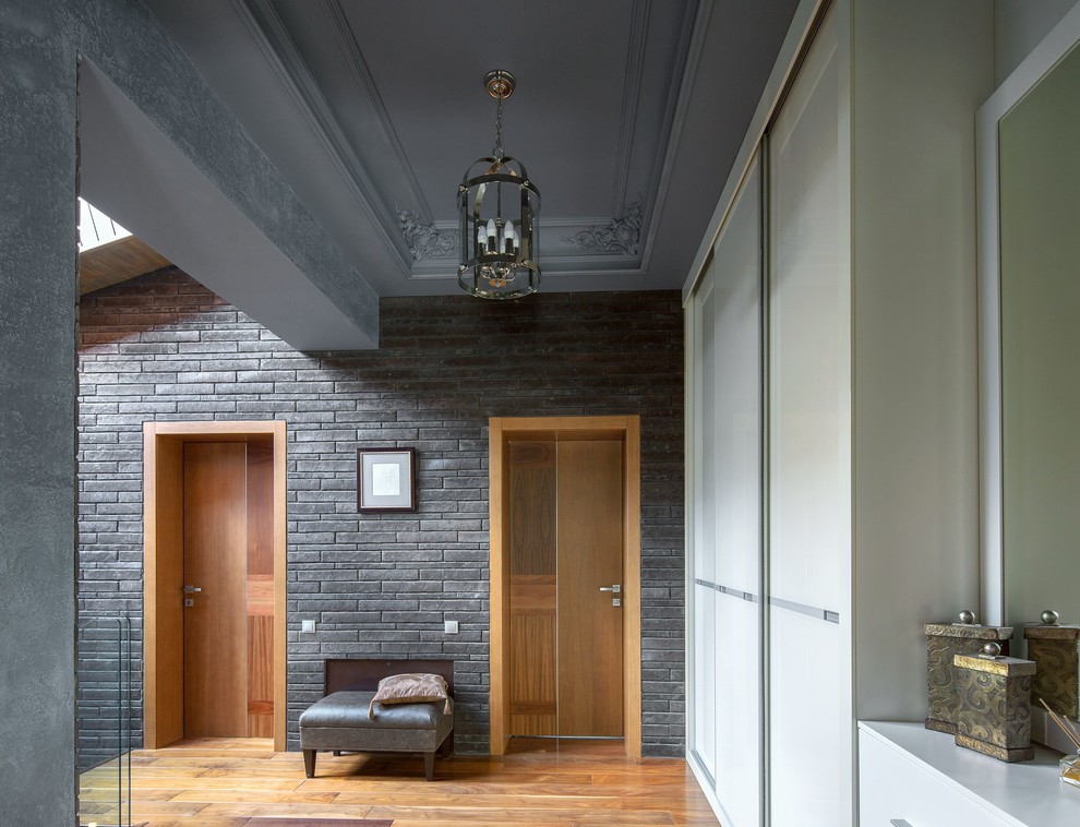 Cette photo montre un grand couloir tendance avec un mur gris, parquet foncé et un sol marron.