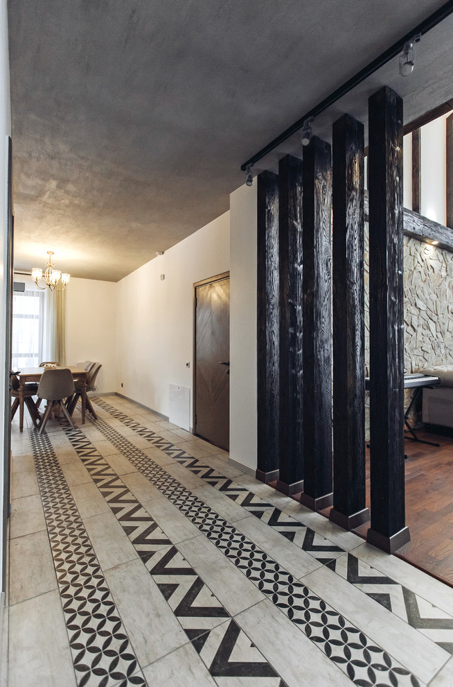 На фото: большой коридор в стиле лофт с белыми стенами, полом из керамической плитки и разноцветным полом