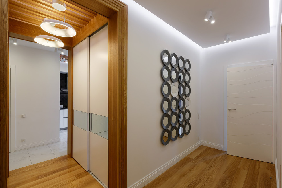 Esempio di un ingresso o corridoio minimal con pareti bianche, pavimento in legno massello medio e pavimento marrone