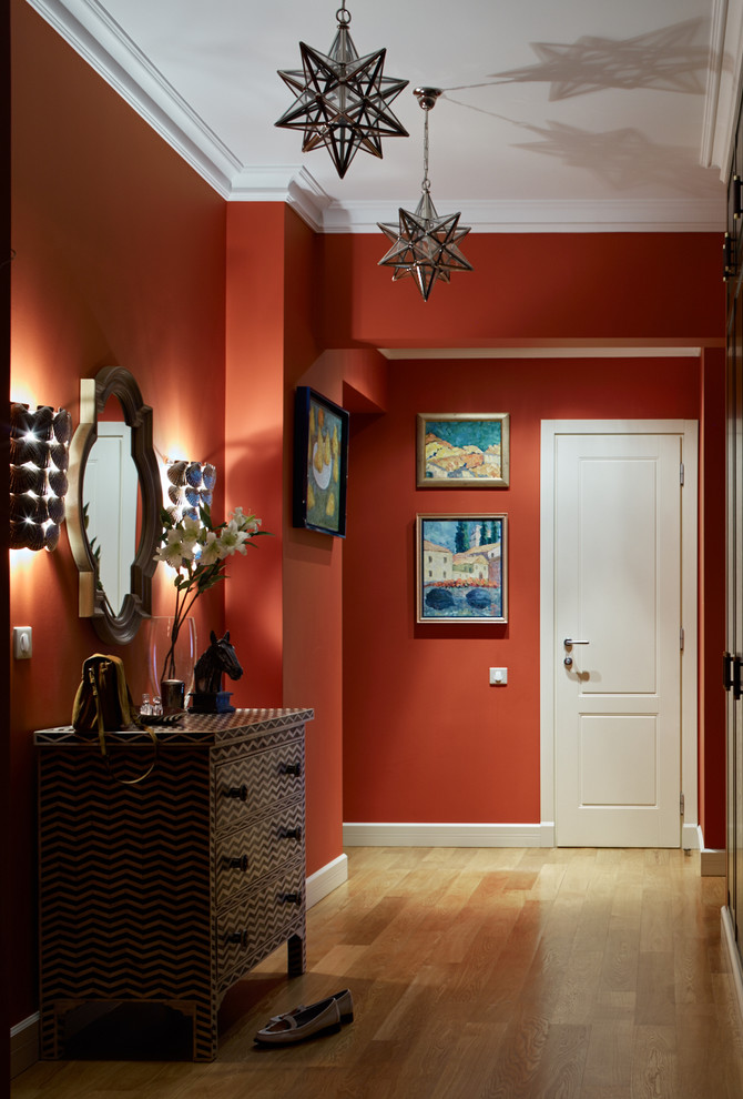 На фото: коридор в стиле неоклассика (современная классика) с красными стенами и паркетным полом среднего тона