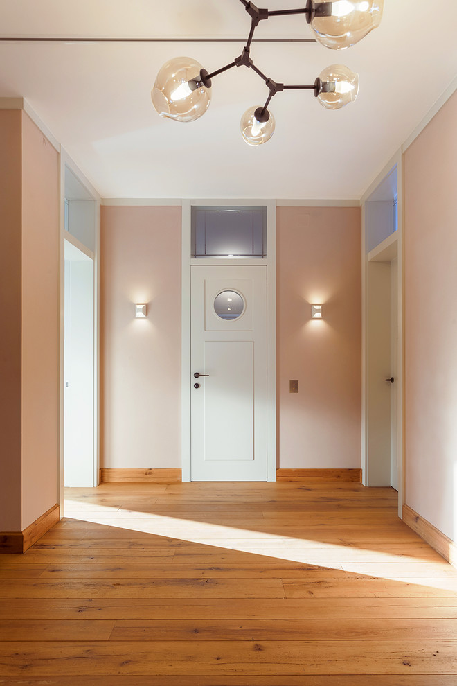 Idee per un ingresso o corridoio minimal di medie dimensioni con pareti rosa e pavimento in legno massello medio