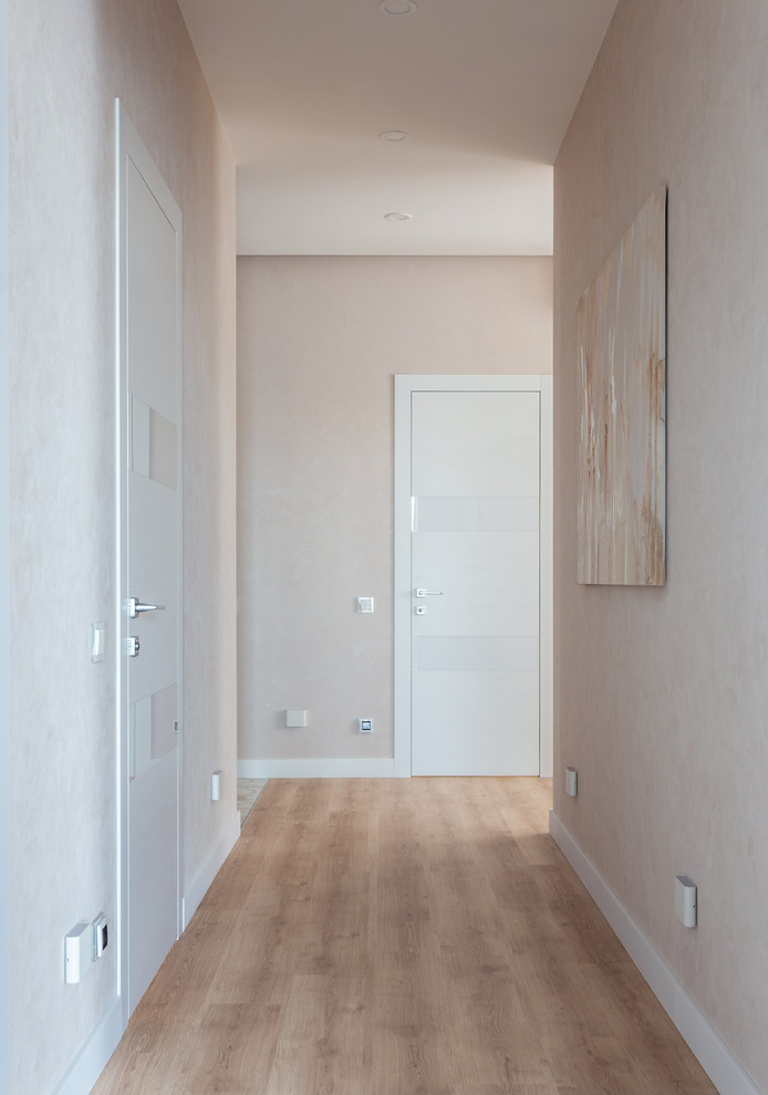 Idées déco pour un couloir contemporain de taille moyenne avec un mur beige, sol en stratifié et un sol beige.