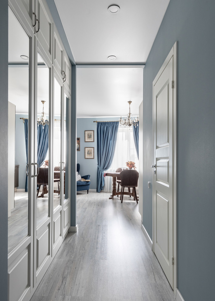 Réalisation d'un couloir tradition de taille moyenne avec un mur bleu, sol en stratifié et un sol gris.