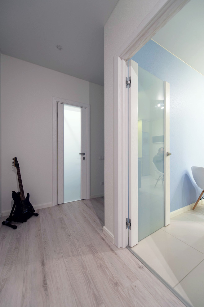 Cette image montre un petit couloir design avec un mur blanc, un sol en carrelage de porcelaine et un sol gris.