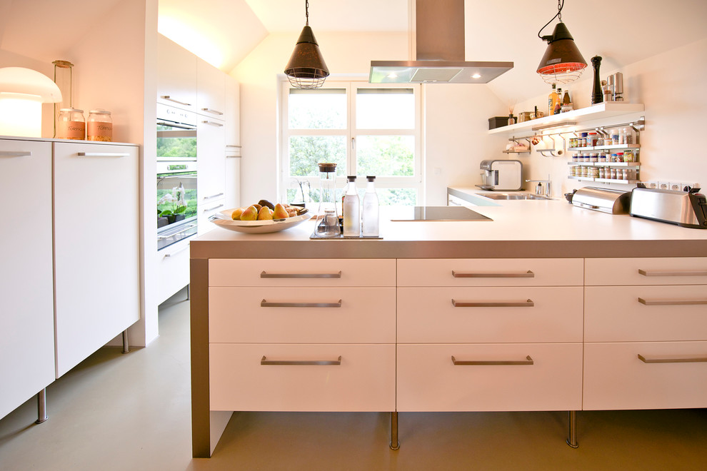 Свежая идея для дизайна: кухня в современном стиле с белыми фасадами, бетонным полом и полуостровом - отличное фото интерьера