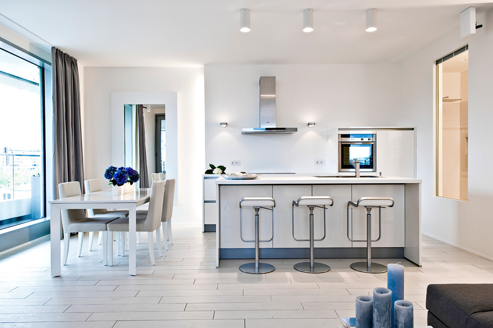 Immagine di una cucina design di medie dimensioni con ante lisce, ante bianche, elettrodomestici da incasso, pavimento in legno verniciato e paraspruzzi bianco