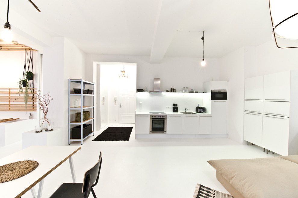 Diseño de cocina lineal escandinava grande abierta sin isla con fregadero encastrado, armarios con paneles lisos, puertas de armario blancas, salpicadero blanco y electrodomésticos de acero inoxidable