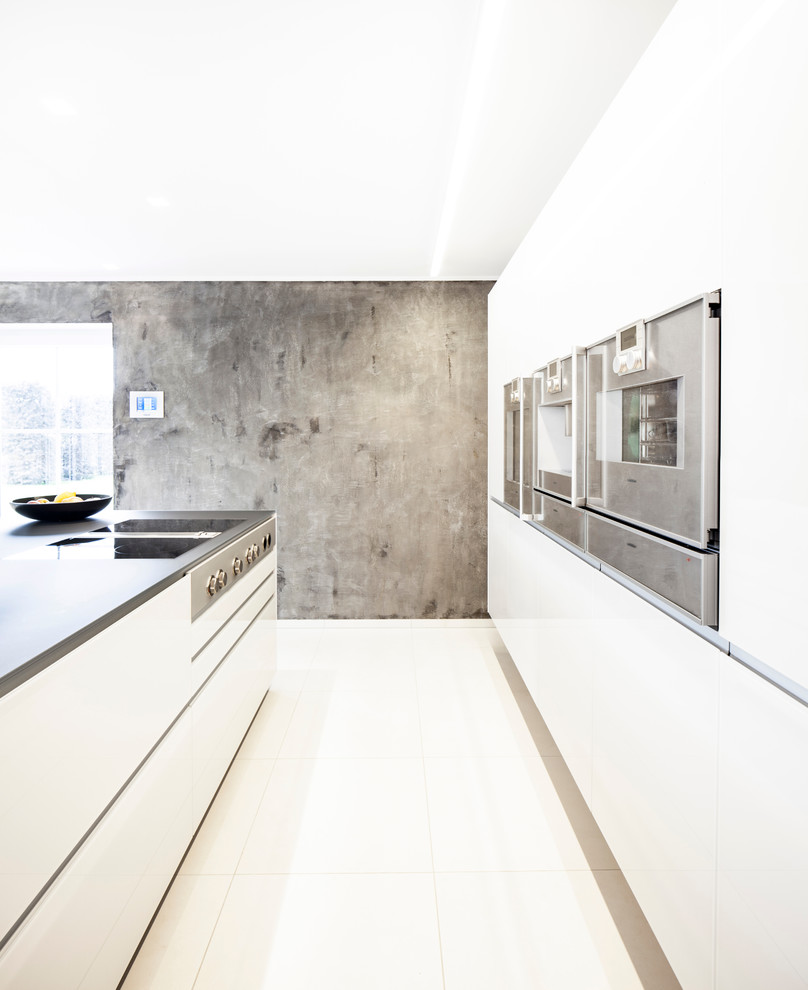 Пример оригинального дизайна: кухня-гостиная в современном стиле с накладной мойкой, плоскими фасадами, белыми фасадами, техникой из нержавеющей стали, бетонным полом и островом
