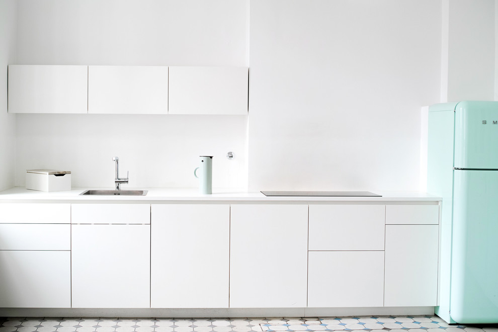 Réalisation d'une cuisine linéaire design de taille moyenne avec des portes de placard blanches.
