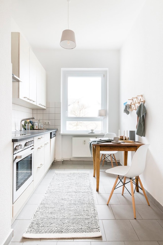 Idéer för att renovera ett mellanstort skandinaviskt grå linjärt grått kök och matrum, med klinkergolv i keramik, släta luckor, beige skåp, vitt stänkskydd, rostfria vitvaror och grått golv