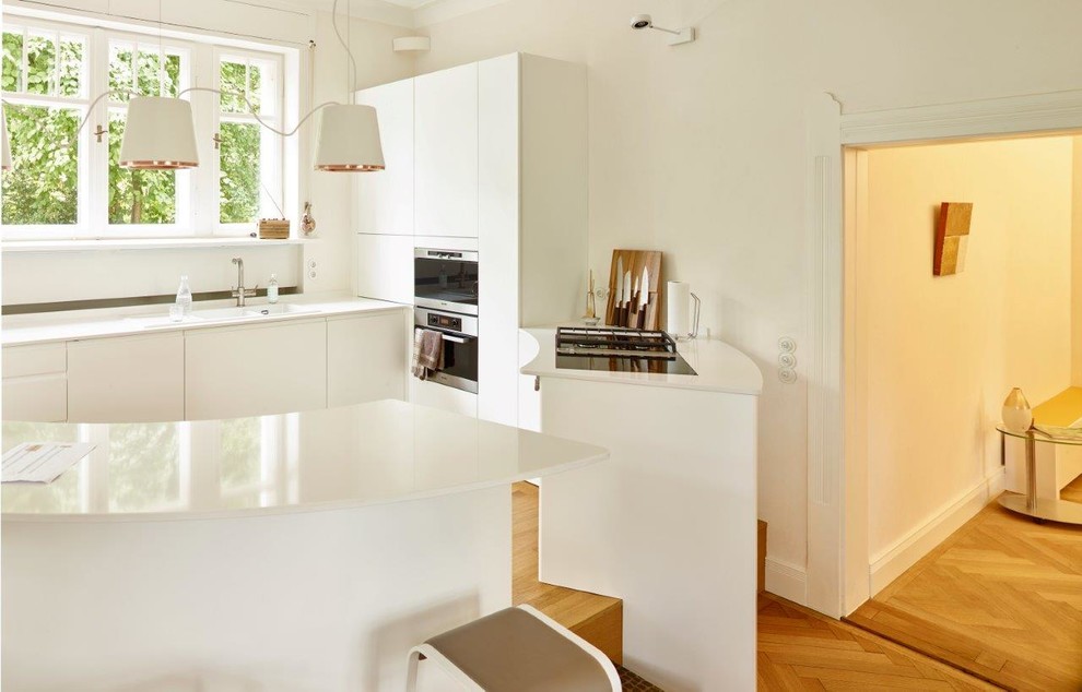 Immagine di una grande cucina scandinava con ante bianche, elettrodomestici da incasso e top bianco