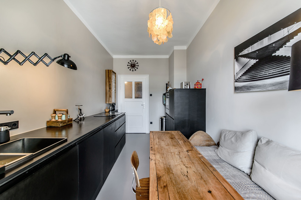 На фото: отдельная, прямая кухня в скандинавском стиле с накладной мойкой, плоскими фасадами, черными фасадами, серым фартуком и полом из линолеума с