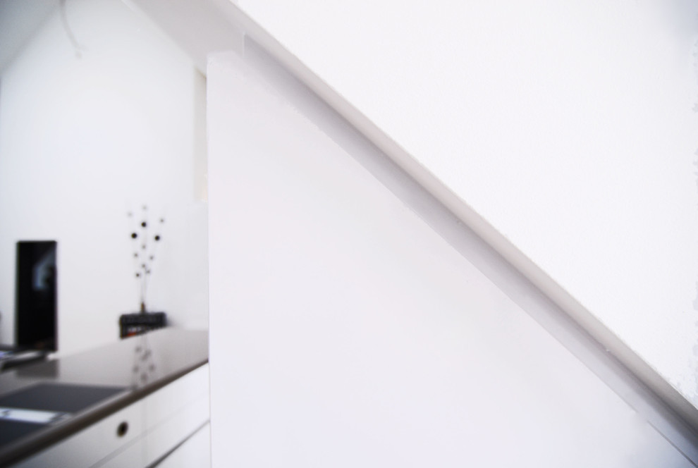 Imagen de cocina contemporánea abierta con armarios con paneles lisos, puertas de armario blancas, encimera de cuarzo compacto, suelo de madera en tonos medios y una isla