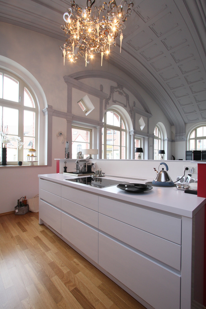 ライプツィヒにある広いモダンスタイルのおしゃれなキッチン (フラットパネル扉のキャビネット、白いキャビネット、無垢フローリング) の写真