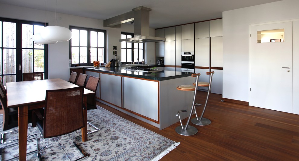 Exempel på ett stort modernt turkos turkost kök, med mörkt trägolv, brunt golv, en undermonterad diskho, släta luckor, skåp i rostfritt stål, bänkskiva i täljsten, rostfria vitvaror och en halv köksö